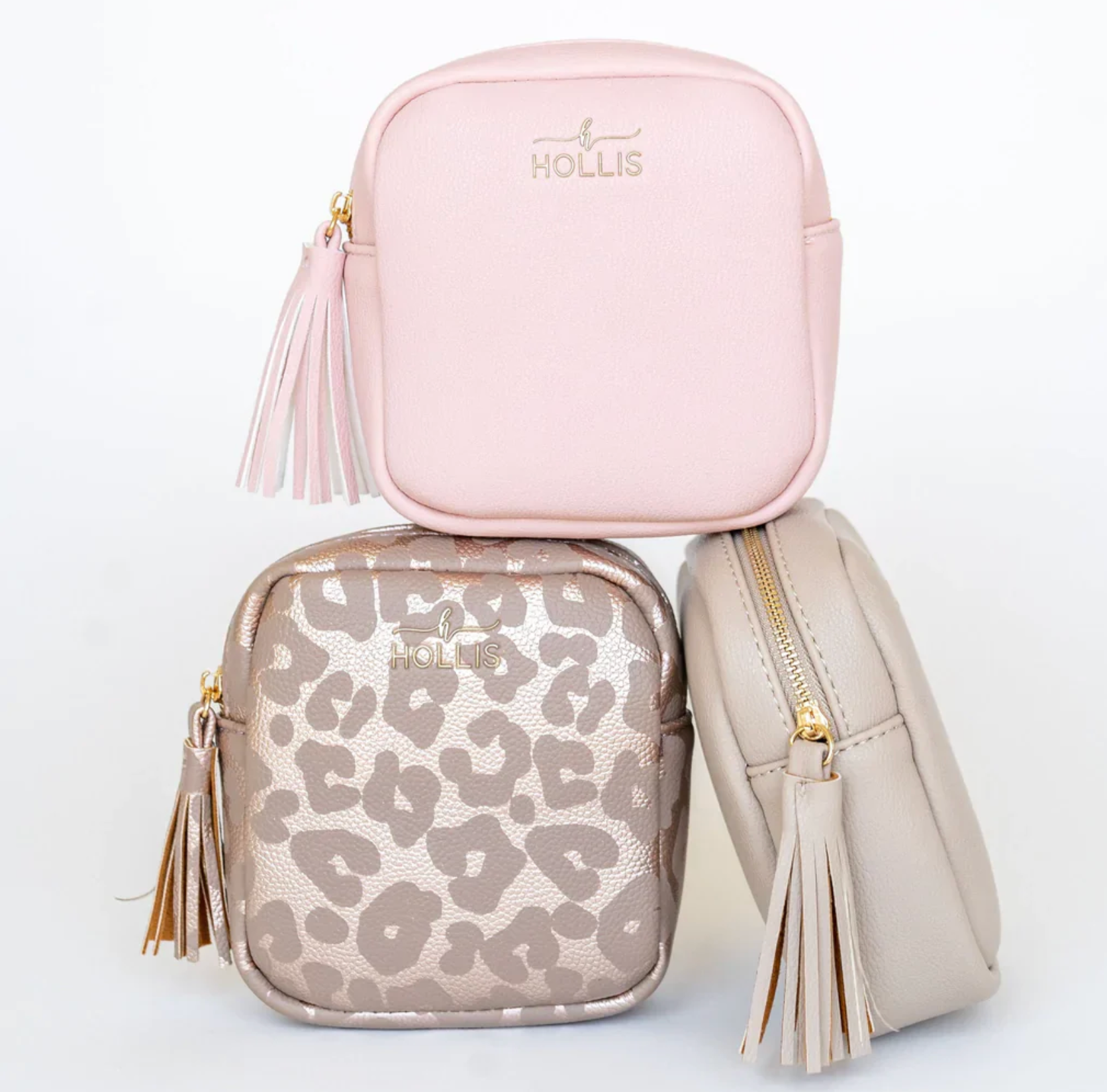 Three bags including a pink, a gold leopard print, and a beige bag with tassels on a light gray background.