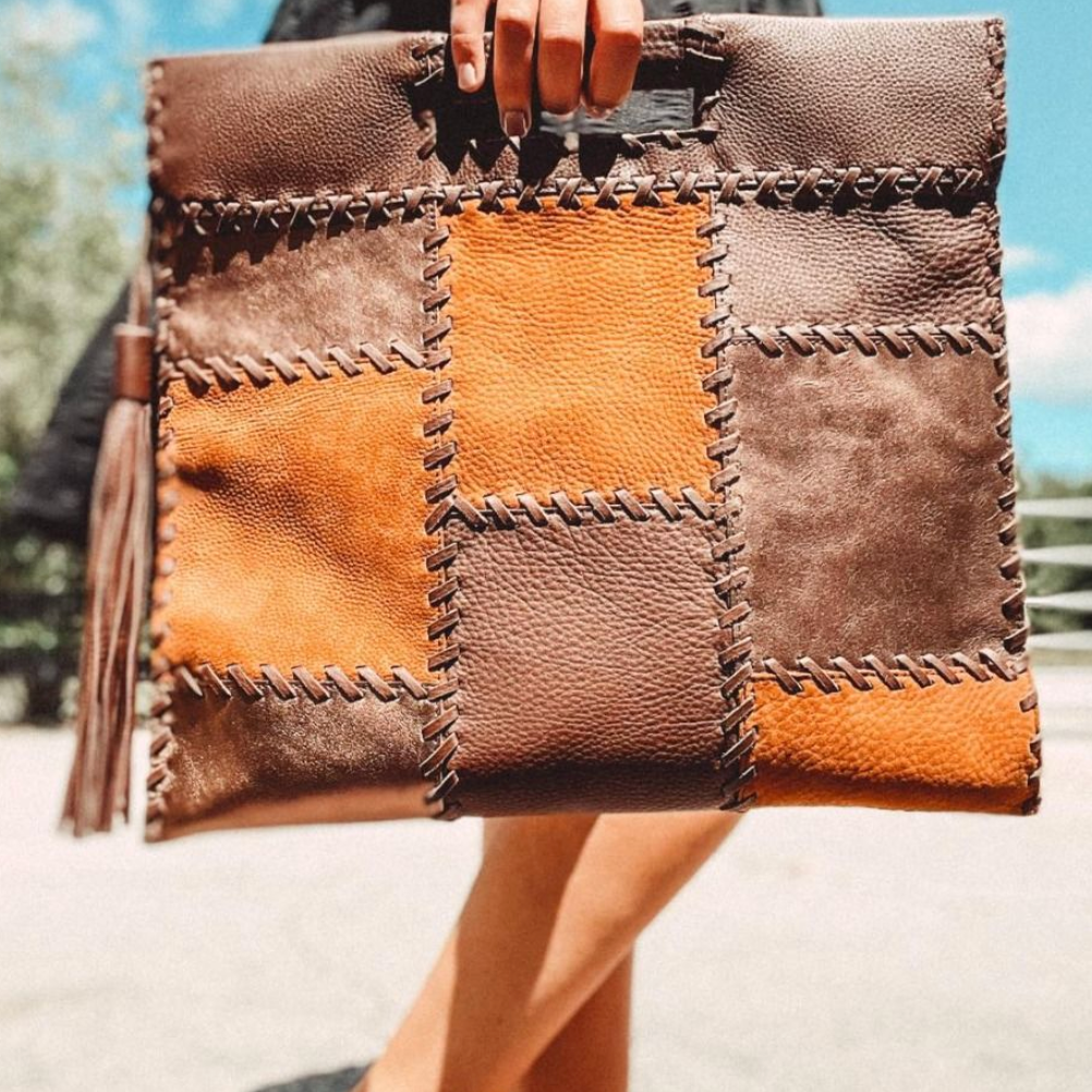 Patchwork leather clutch held by a person with a blurred background