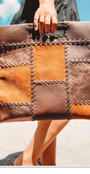 Patchwork leather clutch held by a person with a blurred background