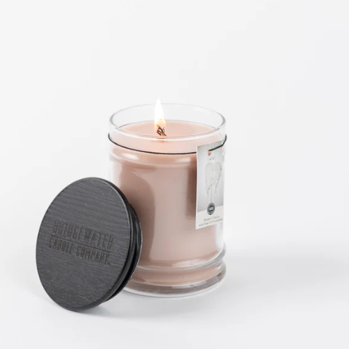 Glass candle with a label and black lid on a white background