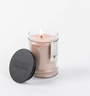 Glass candle with a label and black lid on a white background