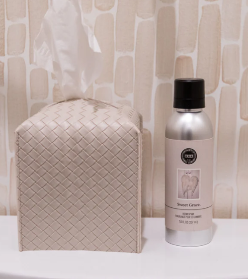 Bottle of Sweet Grace product on a white surface with a textured beige wall background