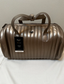Bronze metallic duffel bag with a visible brand tag on a light background
