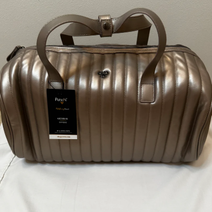 Bronze metallic duffel bag with a visible brand tag on a light background