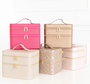 Set of pink, gold, and beige makeup train cases on a white background