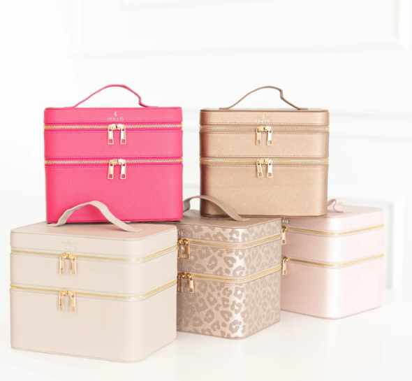 Set of pink, gold, and beige makeup train cases on a white background