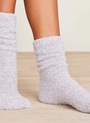White fuzzy socks worn on a light wooden floor