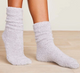 White fuzzy socks worn on a light wooden floor