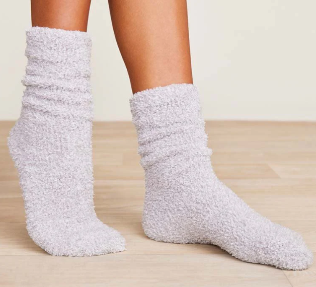 White fuzzy socks worn on a light wooden floor