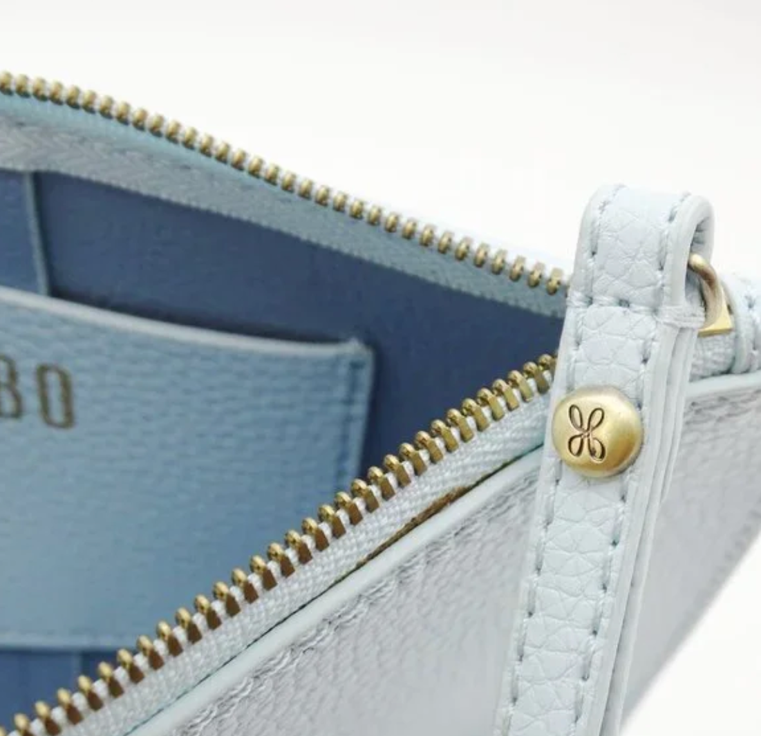 Close-up of a light blue leather wallet with gold zipper and brand logo.