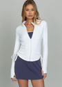Woman wearing a white jacket over a navy top and skirt on a gray background