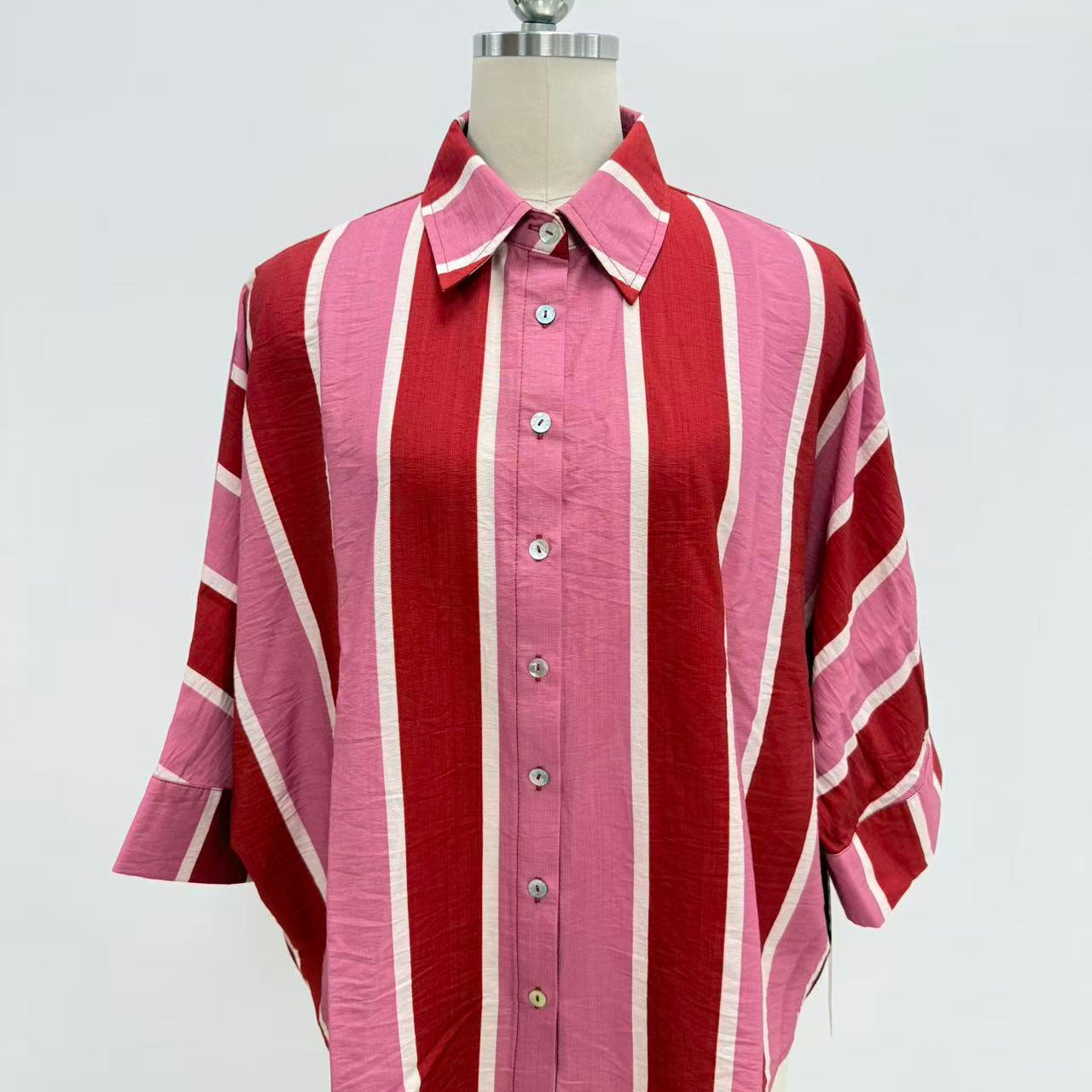 A pink and red striped button-down shirt with white stripes, displayed on a mannequin torso against a white background.