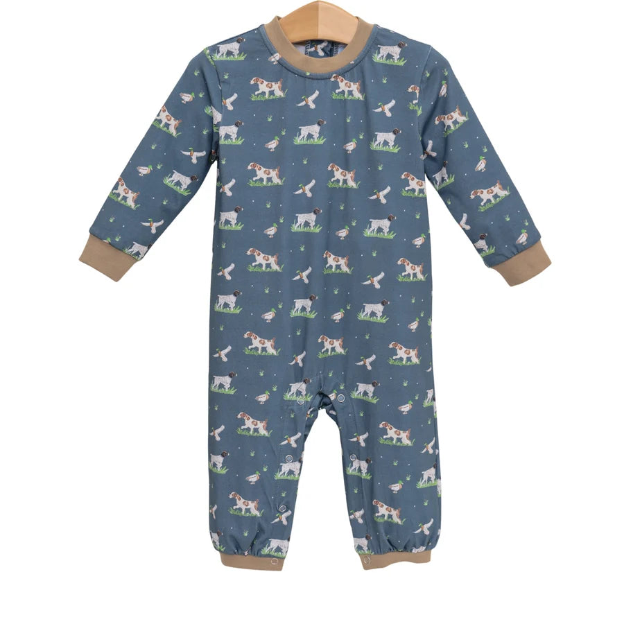 A baby long-sleeve footless one-piece jumpsuit in slate blue, featuring a repeating pattern of dogs, cats, and birds, with tan ribbed cuffs and hem, hanging on a wooden hanger against a white background.