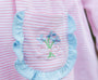 Close-up of a pink and white striped garment with a decorative front pocket trimmed in light blue ruffle. The pocket features embroidered blue flowers with green stems and a pink bow.