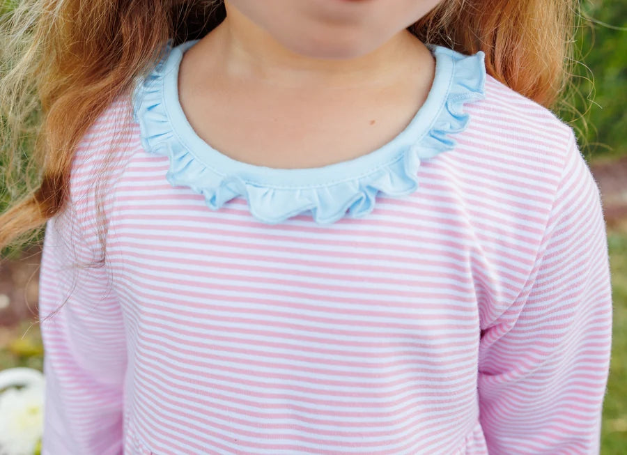 A close-up of a child wearing a pink and white striped long-sleeve top with a light blue ruffled neckline.