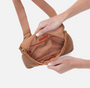 Brown crossbody bag held by a person against a white background
