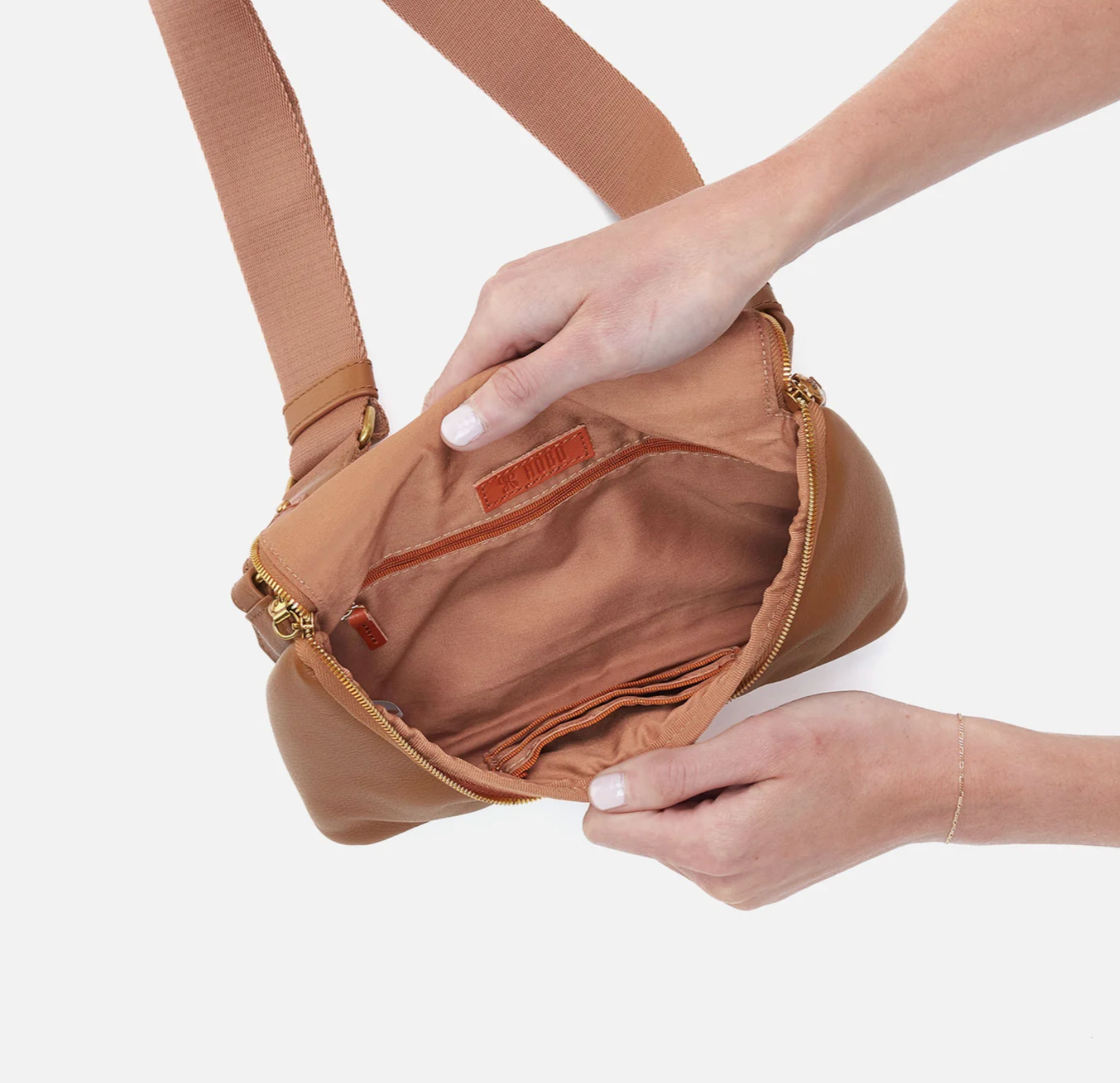 Brown crossbody bag held by a person against a white background