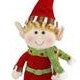 A small elf Christmas ornament with a red hat, green outfit, and red shoes, hanging against a plain white background.