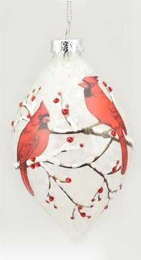 A white Christmas ornament shaped like a teardrop, decorated with two red cardinals perched on branches with small red berries, hanging from a silver cap.