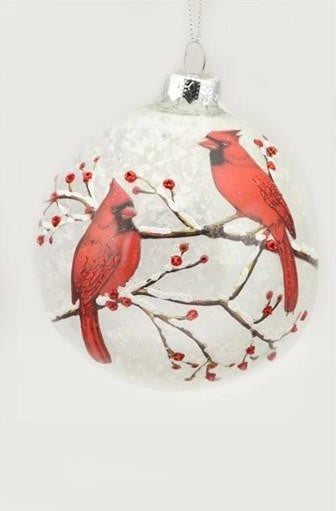 A round clear glass Christmas ornament featuring a printed design of two red cardinals perched on branches with small red berries against a white background.