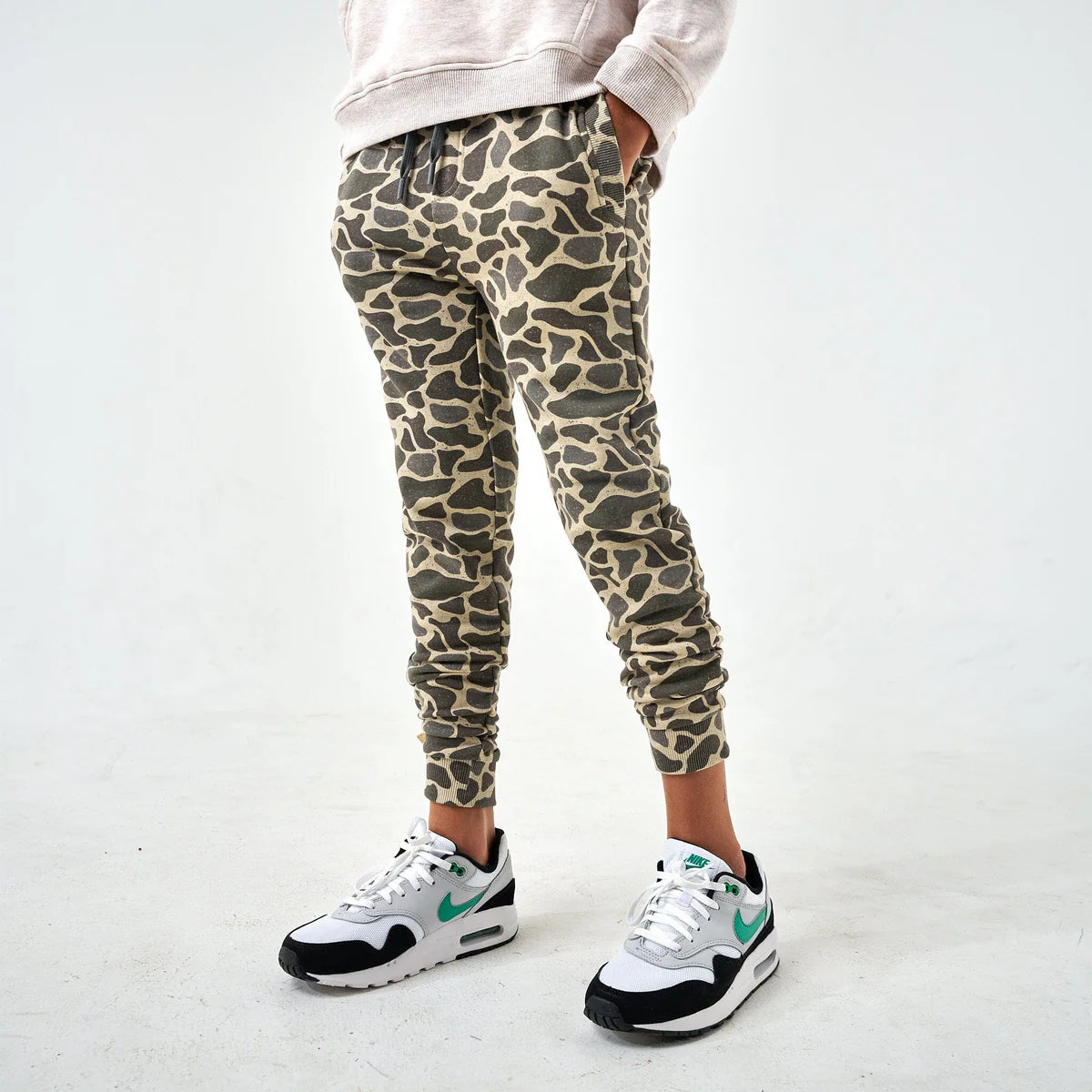 Person wearing leopard print jogger pants and Nike sneakers on a white background