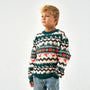 Child wearing a patterned sweater with reindeer and trees on a plain background