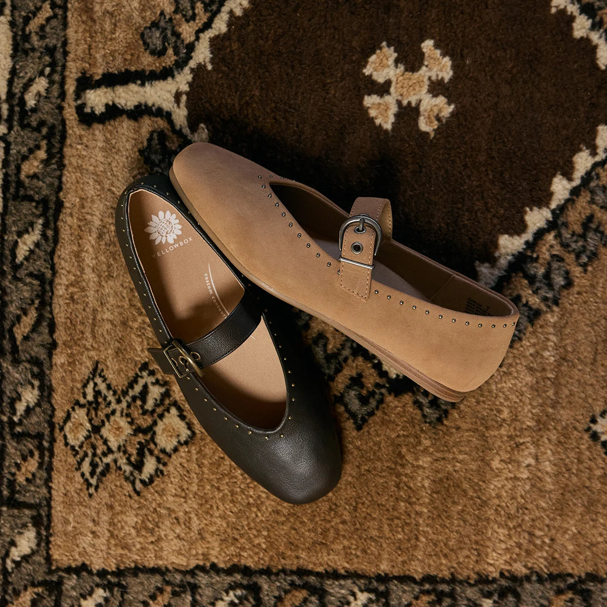 Two Mary Jane style flats, one in dark brown leather and one in tan suede, displayed on a patterned brown rug.