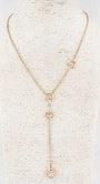 A gold-toned lariat necklace displayed on a textured cream-colored mannequin bust. The necklace features a fine chain, a central Y-shaped drop with three interlocking circular links, and two smaller circular links on the upper strap.