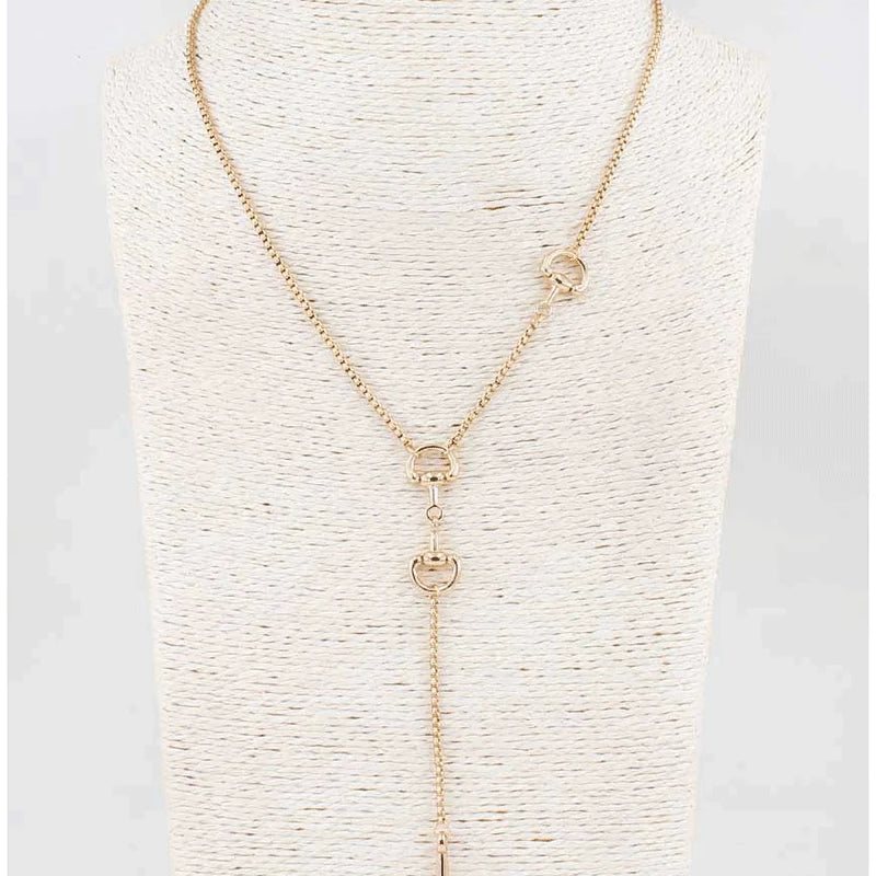 A gold-toned lariat necklace displayed on a textured cream-colored mannequin bust. The necklace features a fine chain, a central Y-shaped drop with three interlocking circular links, and two smaller circular links on the upper strap.