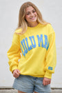 Person wearing a yellow sweatshirt with blue text against a light background
