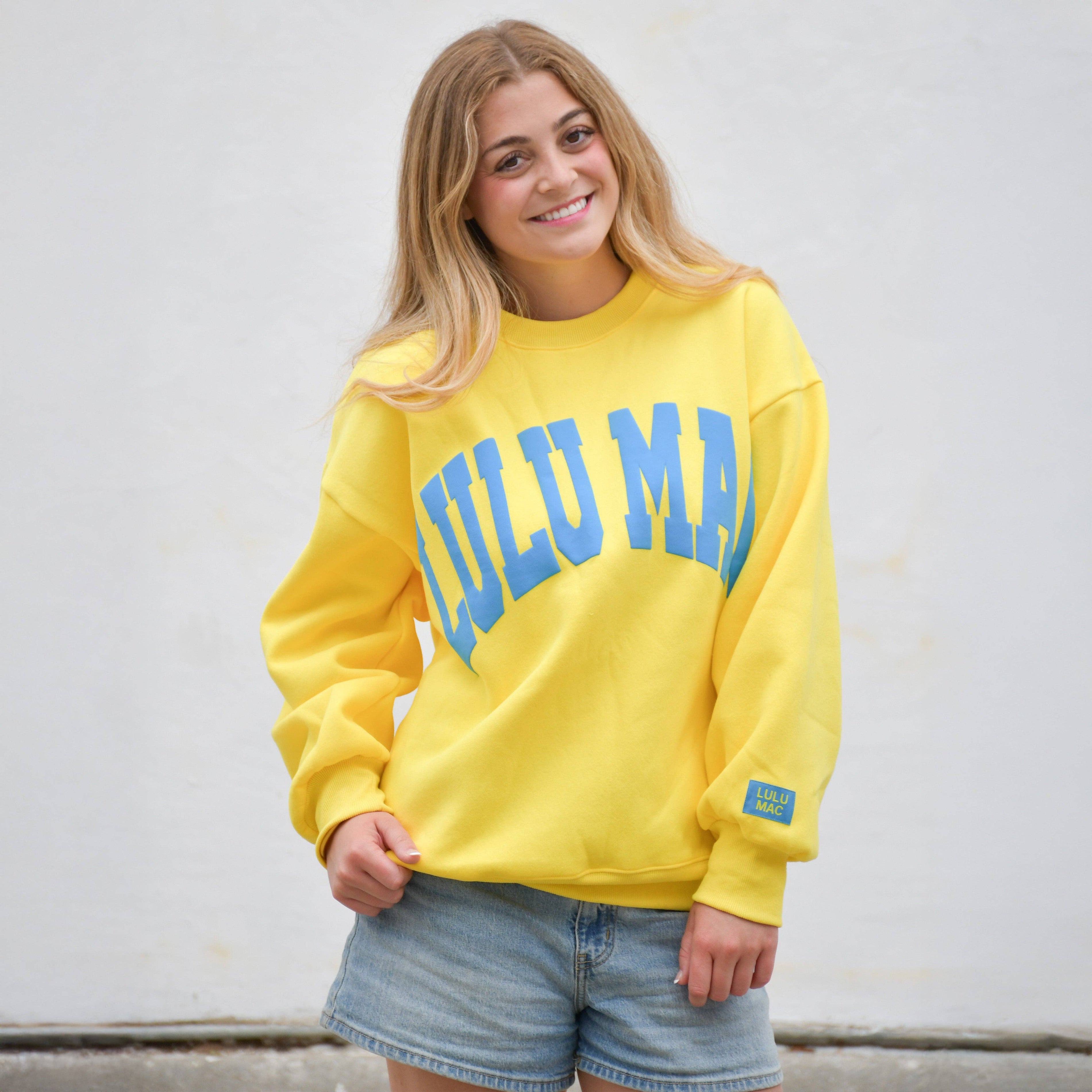 Person wearing a yellow sweatshirt with blue text against a light background