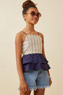 Young girl wearing a striped top and denim shorts against a beige background