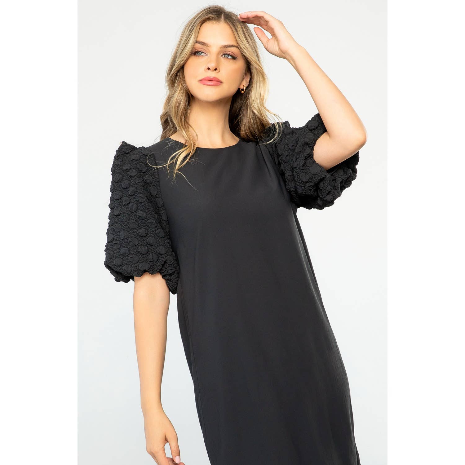 Woman wearing a black dress with floral sleeves on a white background