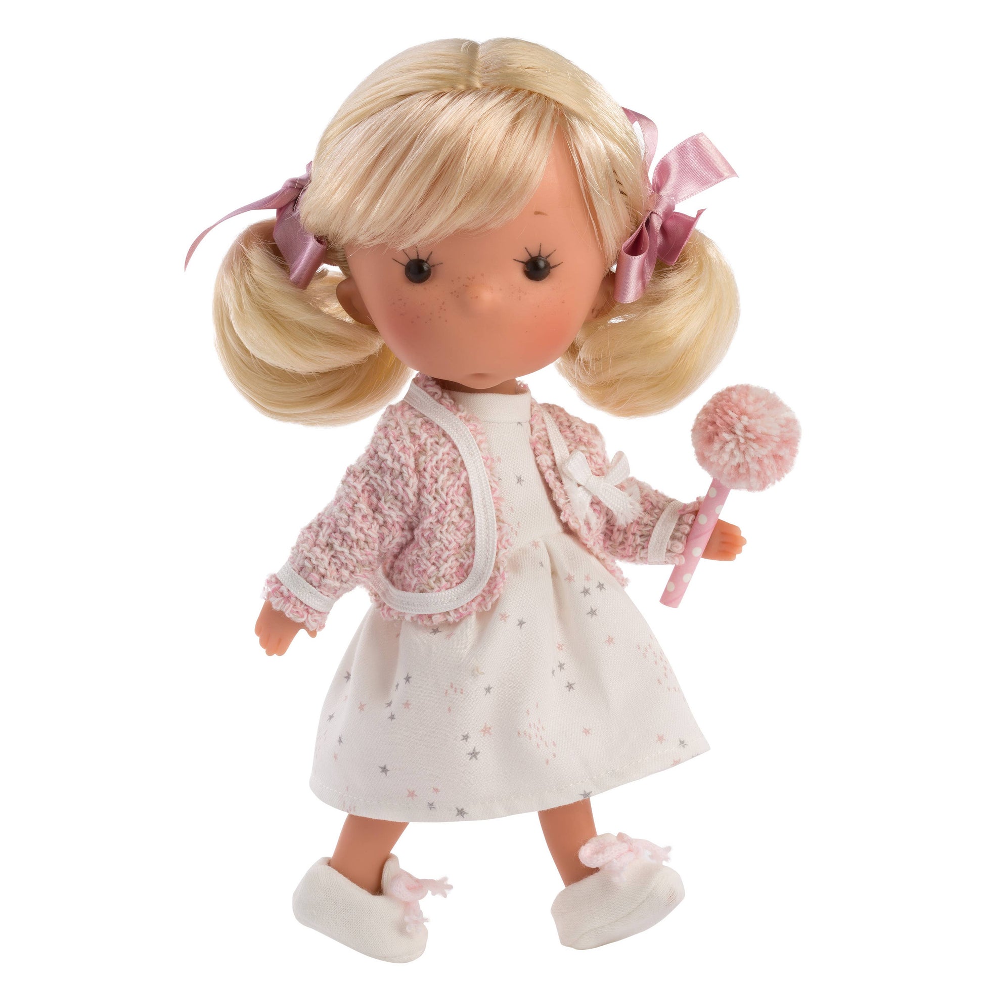 Doll with blonde hair in pigtails, wearing a white dress with pink accents and holding a pink toy.