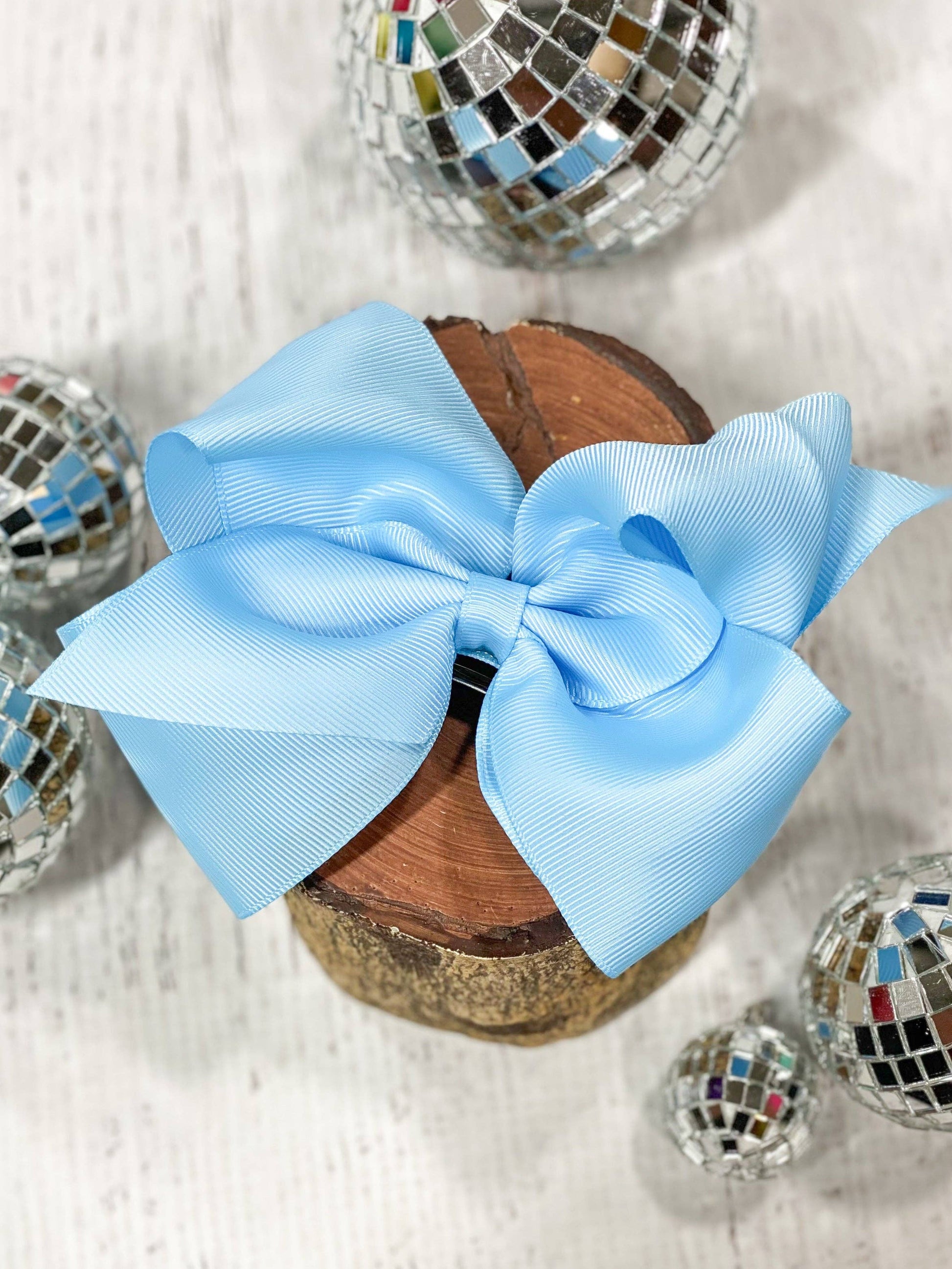 Blue bow on a wooden block with disco balls in the background