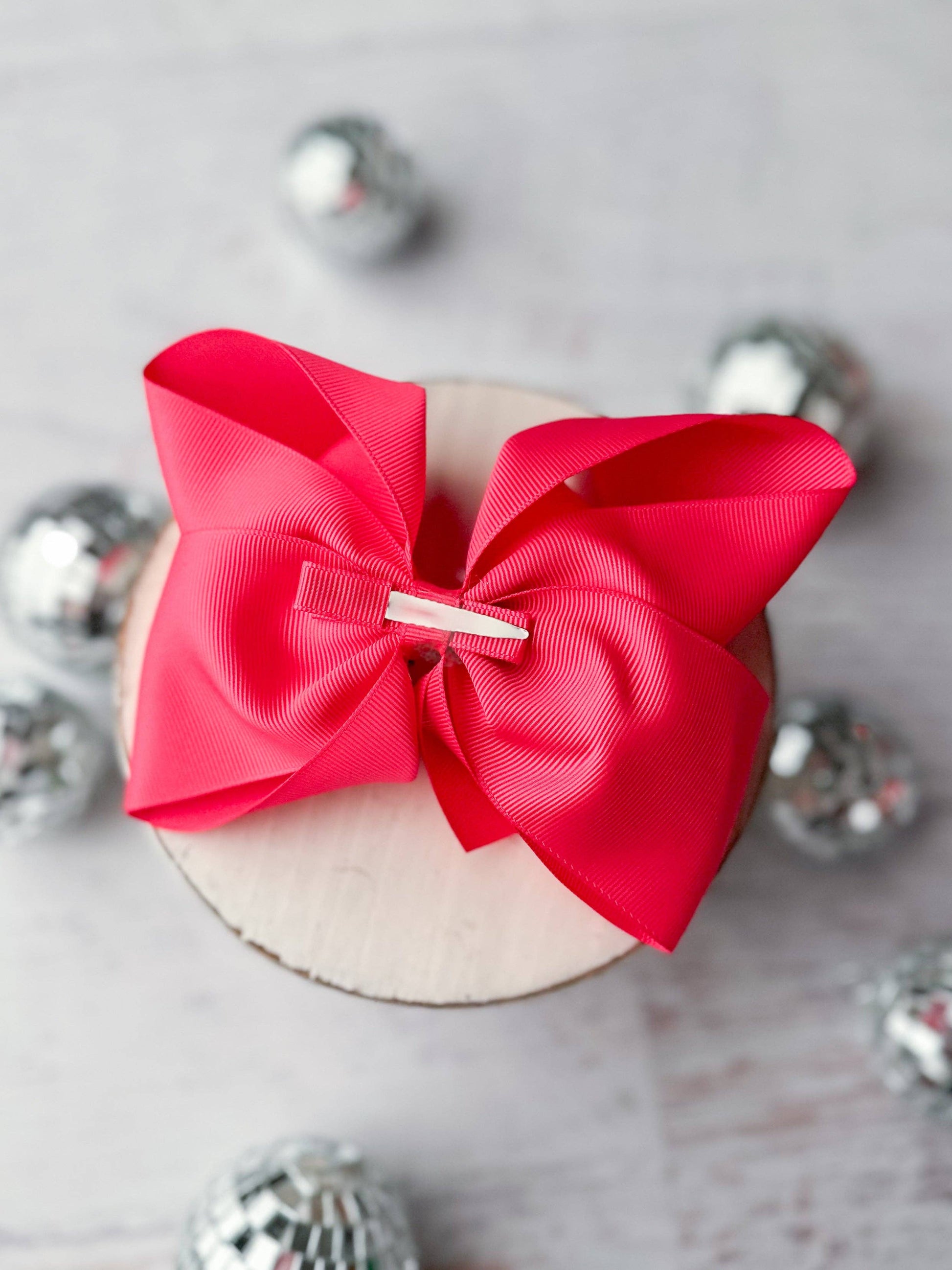 Red bow on a wooden block with silver knobs in the background