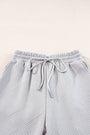 Light gray textured pants with drawstring on a light beige background