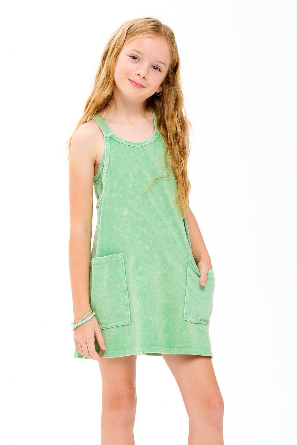 Young girl wearing a green dress with pockets on a white background