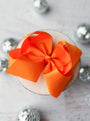 Orange bow on a white surface with silver decorative elements