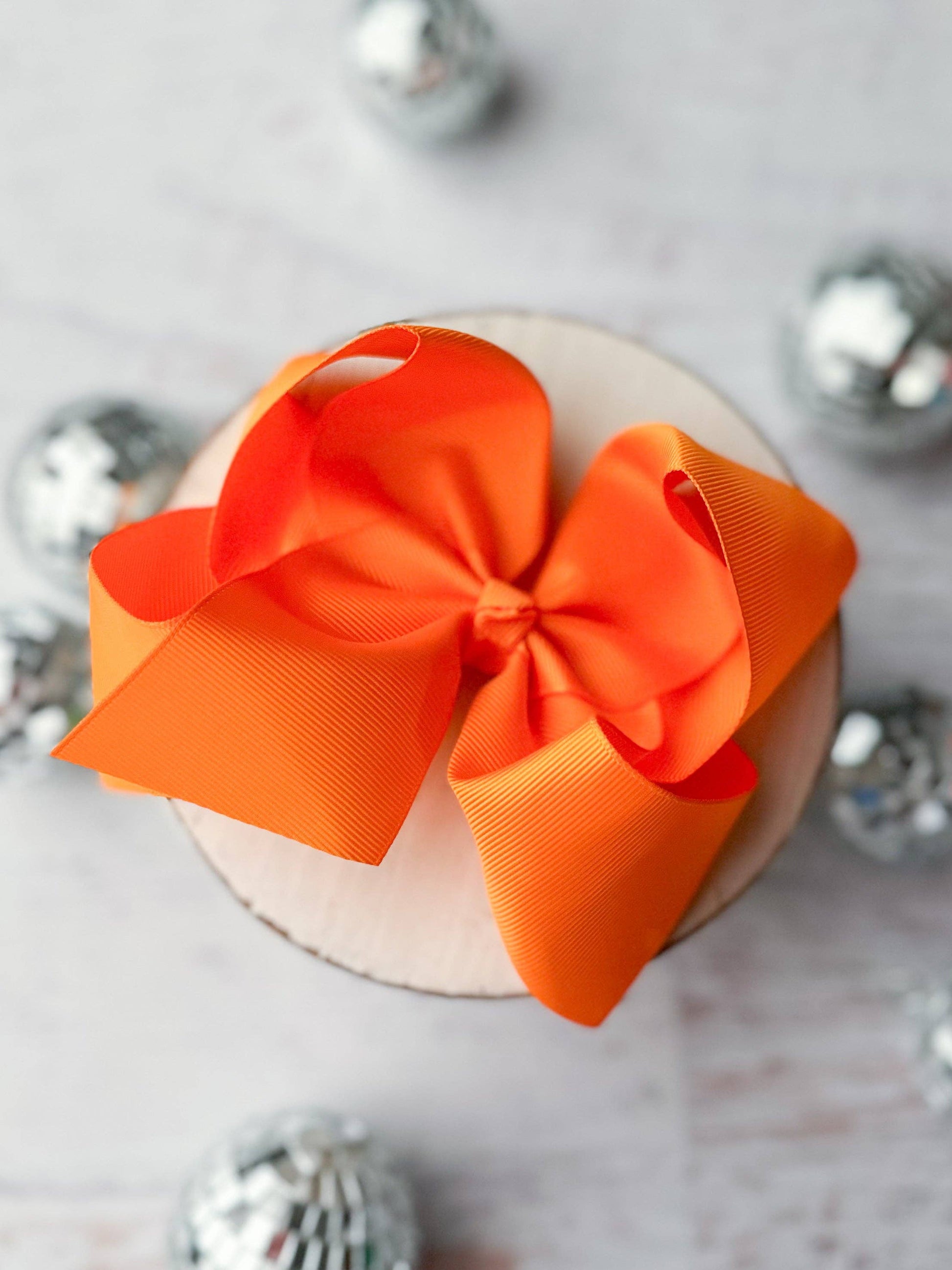Orange bow on a white surface with silver decorative elements