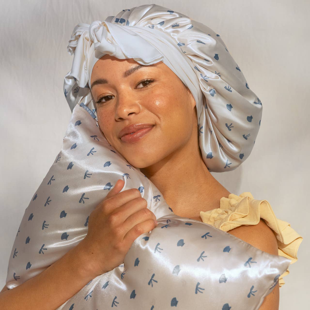 Woman wearing a satin hair cap with floral pattern against a plain background