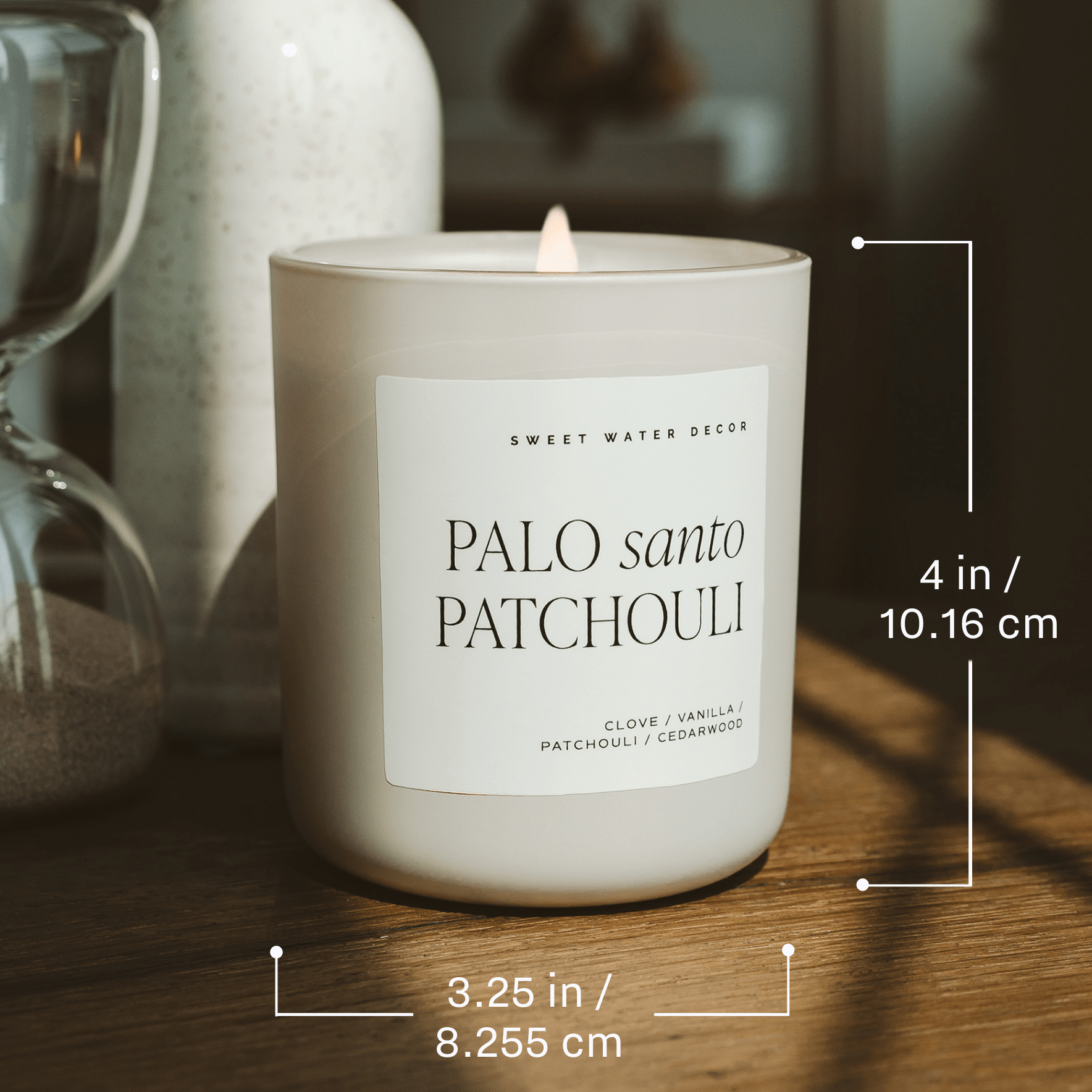 Candle with a label reading 'Palo Santo Patchouli' on a wooden surface, with measurements displayed.