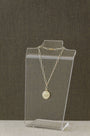 A delicate gold chain necklace with a round medallion pendant displaying '825' sterling silver purity stamp, displayed on a clear acrylic stand against a dark textured background.