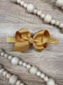 Gold bow headband on a wooden surface with decorative beads