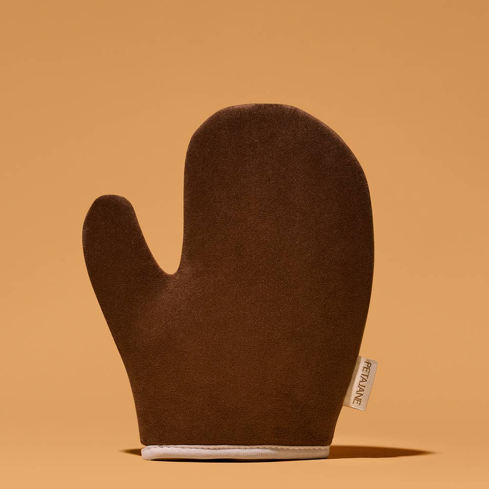 Brown self tanning mitt with a brand label on an orange background