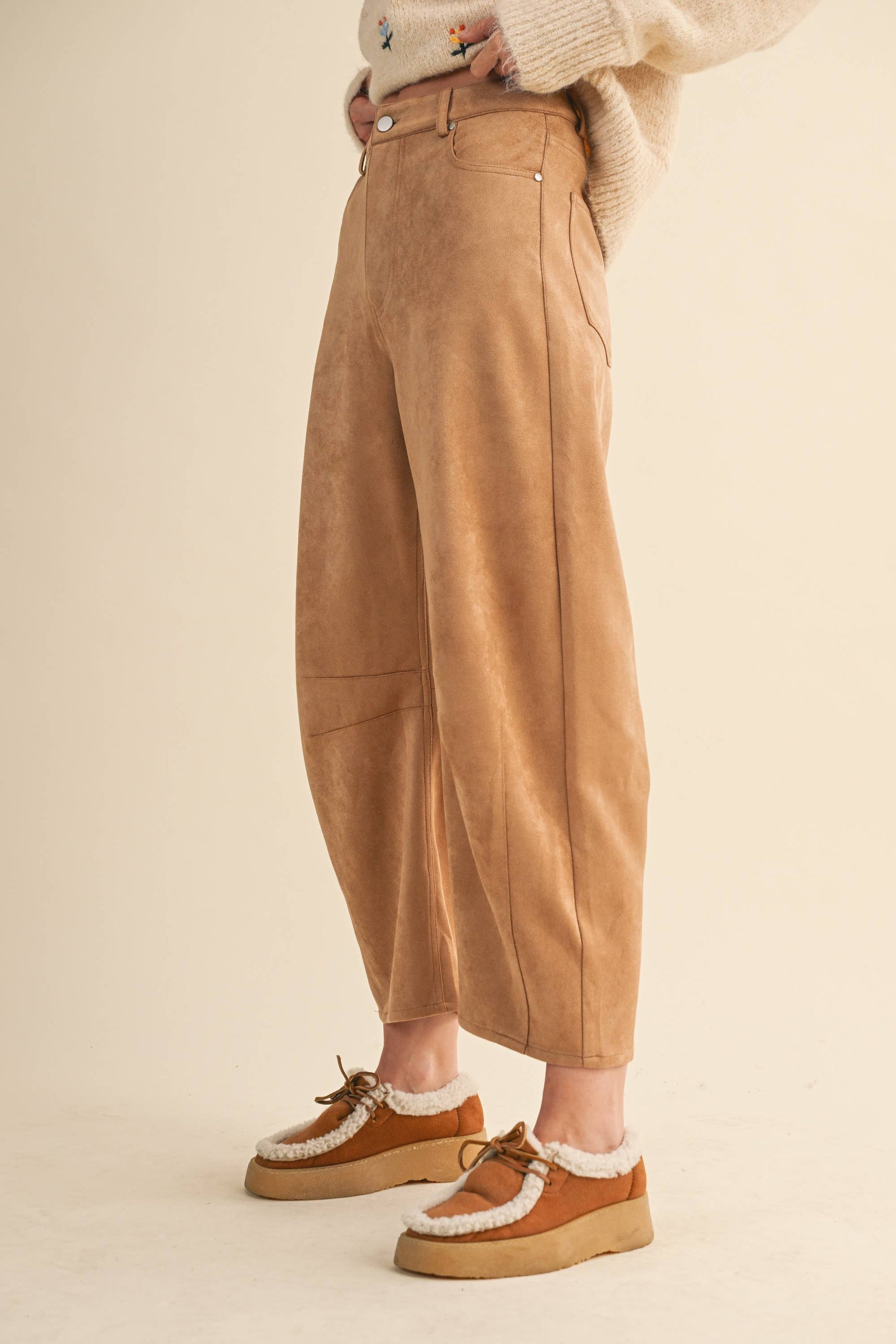 Person wearing tan pants and brown shoes on a beige background