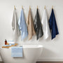 Set of six towels in various colors hanging on hooks above a bathtub.