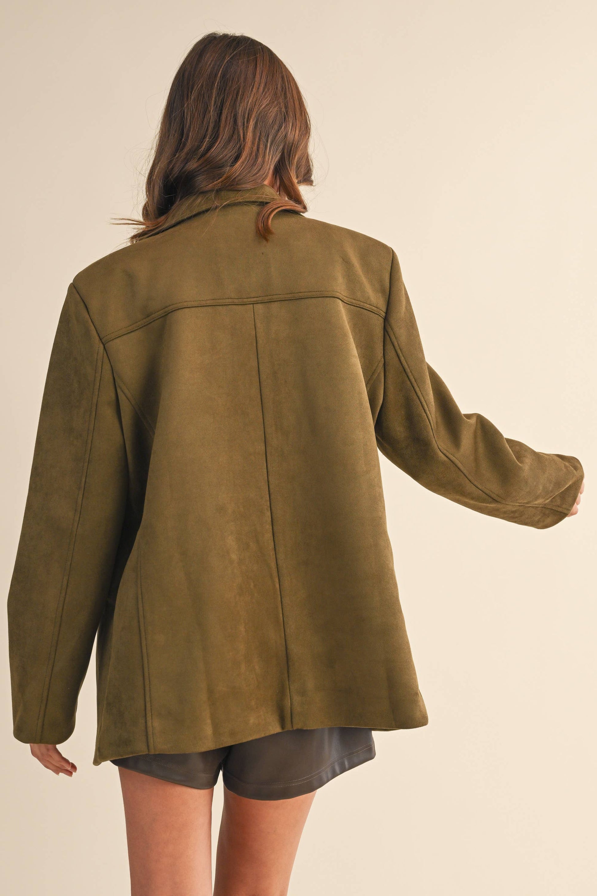 Person wearing a green jacket on a beige background