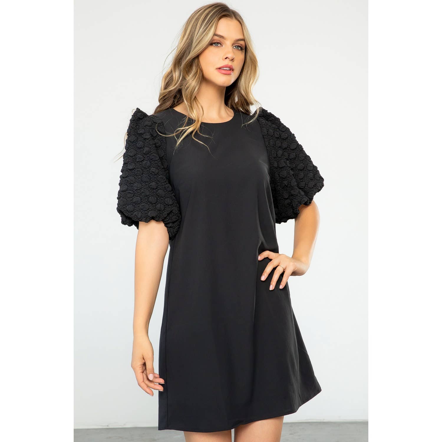 Woman wearing a black dress with floral sleeves against a white background