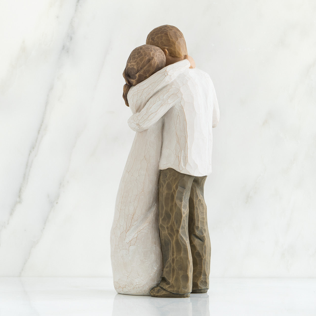 Two stone sculptures of people hugging on a white background